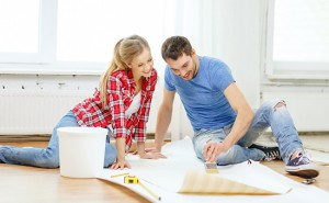 молодая пара в своей новой квартире обсуждает предстоящий ремонт, сидя на полу